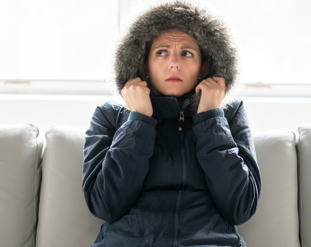 Woman in coat indoors cold due to untreated thyroid condition