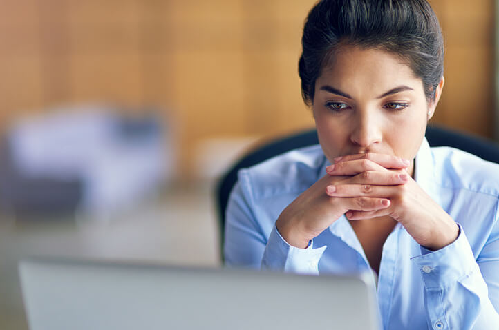 A worried young woman stares at computer screen